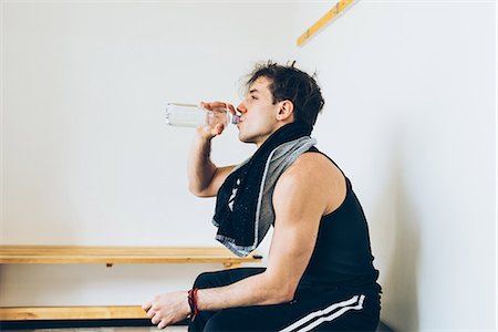 Man sitting in changing room drinking water from plastic bottle Stock Photo - Premium Royalty-Free, Code: 649-08577850
