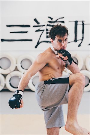 simsearch:614-08879113,k - Man in gym wearing boxing gloves in kickboxing stance looking at camera Stockbilder - Premium RF Lizenzfrei, Bildnummer: 649-08577876