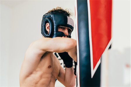 simsearch:614-07194427,k - Man wearing head protector sparring with punchbag Stock Photo - Premium Royalty-Free, Code: 649-08577881
