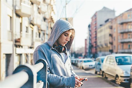 simsearch:649-09269215,k - Man in urban area wearing hooded top and headphones looking down at smartphone Stock Photo - Premium Royalty-Free, Code: 649-08577903