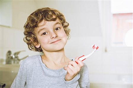 simsearch:649-08563488,k - Boy in bathroom holding toothbrush looking at camera smiling Stockbilder - Premium RF Lizenzfrei, Bildnummer: 649-08577934