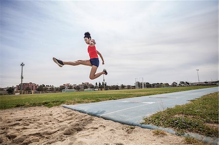 salto em distância - Young female long jumper jumping mid air at sport facility Foto de stock - Royalty Free Premium, Número: 649-08578013