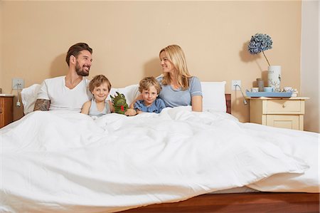 Mother and father in bed with sons and toy dragon Stock Photo - Premium Royalty-Free, Code: 649-08578035