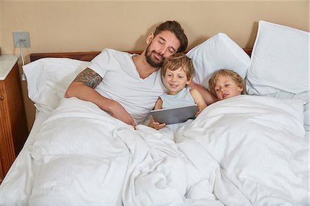 family and bed and three people and boy - Father and sons in bed using digital tablet Stock Photo - Premium Royalty-Free, Code: 649-08578041