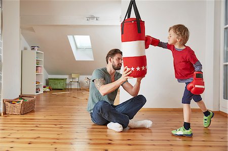 sitting on floor - Father holding punchbag for son Stock Photo - Premium Royalty-Free, Code: 649-08578059