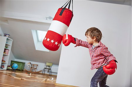 Boy wearing boxing gloves punching punch bag Foto de stock - Sin royalties Premium, Código: 649-08578065
