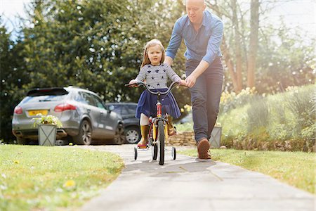 dad teaching - Father teaching daughter to ride bicycle on street Stock Photo - Premium Royalty-Free, Code: 649-08578146