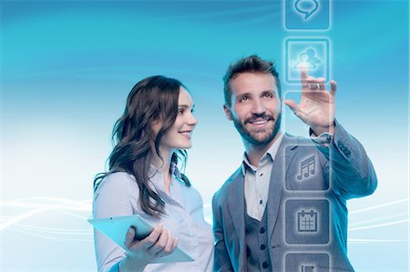 Man and woman using graphical screen, man touching icon Stock Photo - Premium Royalty-Free, Code: 649-08660502