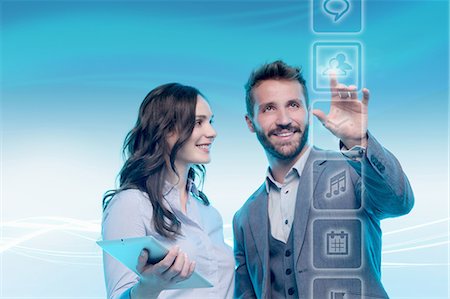 disruptive technology - Man and woman using graphical screen, man touching icon Stock Photo - Premium Royalty-Free, Code: 649-08660502