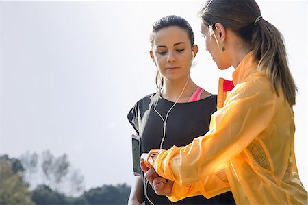Two female friends outdoors, young woman showing friend activity tracker Stock Photo - Premium Royalty-Free, Code: 649-08660554