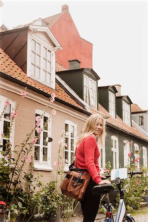 Woman pushing bicycle past houses, Aarhus, Denmark Stock Photo - Premium Royalty-Free, Code: 649-08661096