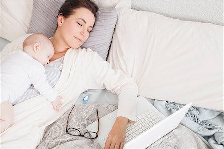 exhausted mother with baby - Mother and baby sleeping together on bed, laptop beside them Stock Photo - Premium Royalty-Free, Code: 649-08661264