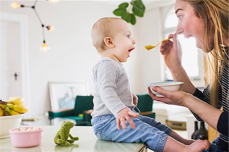 Baby girl mimicking mother whilst eating  at kitchen table Stockbilder - Premium RF Lizenzfrei, Bildnummer: 649-08661488