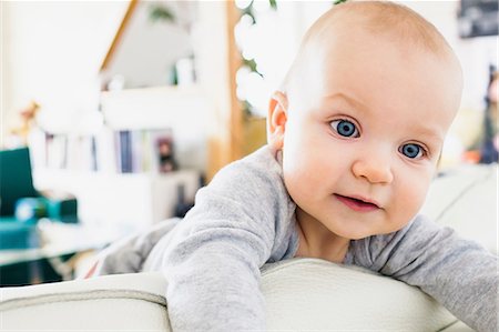 Blue eyed baby girl climbing on sofa Stock Photo - Premium Royalty-Free, Code: 649-08661517