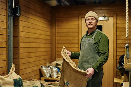 portrait real person not smiling - Portrait of male coffee shop owner holding coffee bean sack in store room Stock Photo - Premium Royalty-Free, Code: 649-08661600