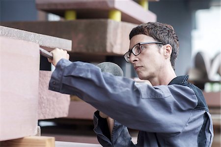 Stonemason using chisel and mallet on block of stone Stock Photo - Premium Royalty-Free, Code: 649-08661853