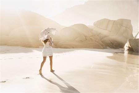 quitasol - Rear view of woman strolling with parasol on sunlit beach, Cape Town, South Africa Foto de stock - Sin royalties Premium, Código: 649-08661916