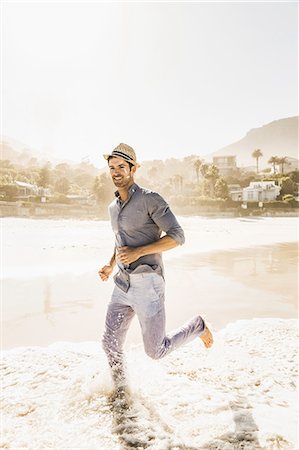 Young man running in sunlit sea, Cape Town, South Africa Stock Photo - Premium Royalty-Free, Code: 649-08661954