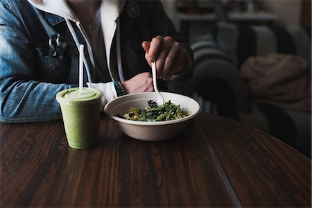 smoothie bowl - Young man sitting at table, eating salad, mid section Stock Photo - Premium Royalty-Free, Code: 649-08662052