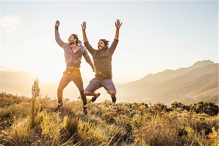 simsearch:649-08662119,k - Friends on grassland, arms raised jumping Foto de stock - Sin royalties Premium, Código: 649-08662135