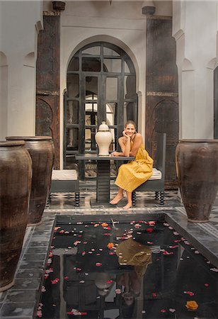 Young woman sitting by petal covered water feature, Marrakesh, Morocco Stock Photo - Premium Royalty-Free, Code: 649-08662278