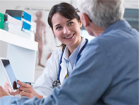 doctor advising patient in hospital - Doctor sharing health information on digital tablet with patient in clinic Stock Photo - Premium Royalty-Free, Code: 649-08702119