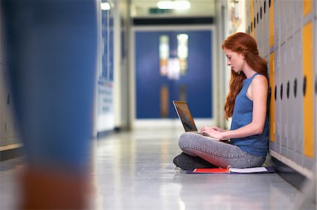 simsearch:649-07648135,k - Young female college student sitting on locker room floor typing on laptop Foto de stock - Royalty Free Premium, Número: 649-08702361