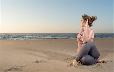 Mature woman practising yoga on a beach at sunset, sitting cross legged Stock Photo - Premium Royalty-Free, Code: 649-08702380