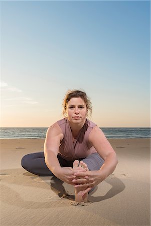 Mature woman practising yoga on a beach at sunset, portrait touching toes Foto de stock - Sin royalties Premium, Código: 649-08702381