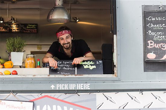 Portrait of young man at hatch of fast food van Stock Photo - Premium Royalty-Free, Image code: 649-08702411