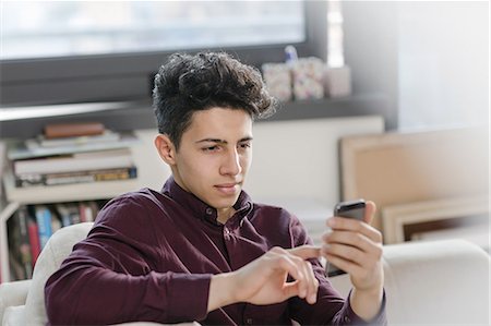 simsearch:649-08702598,k - Young man on sofa texting on smartphone Stock Photo - Premium Royalty-Free, Code: 649-08702594