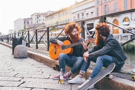 simsearch:649-08765972,k - Young male hipster twins with red hair and beards playing guitar on canal waterfront Photographie de stock - Premium Libres de Droits, Code: 649-08702662