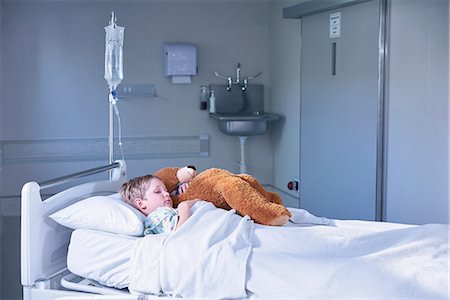 sick boy with teddy - Boy patient in bed hugging teddy bear on hospital children's ward Stock Photo - Premium Royalty-Free, Code: 649-08702747