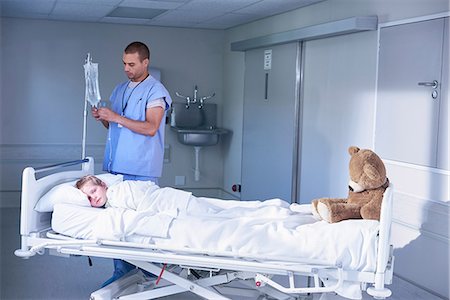 simsearch:649-08702747,k - Male nurse adjusting intravenous drip for boy patient in hospital children's ward Stock Photo - Premium Royalty-Free, Code: 649-08702748