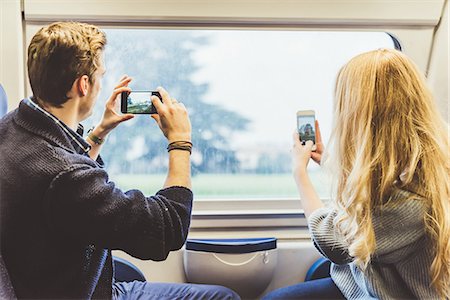 simsearch:649-08702811,k - Young couple taking smartphone photographs through train carriage window, Italy Fotografie stock - Premium Royalty-Free, Codice: 649-08702758