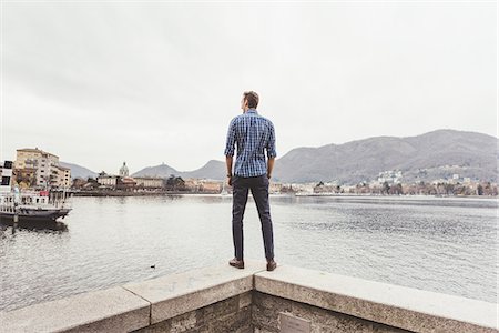 Rear view of young man standing on harbour wall looking out, Lake Como, Italy Stock Photo - Premium Royalty-Free, Code: 649-08702807
