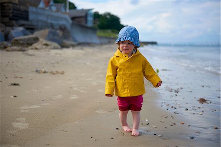 simsearch:649-06717318,k - Baby girl on beach wearing sunhat and raincoat Foto de stock - Royalty Free Premium, Número: 649-08703208