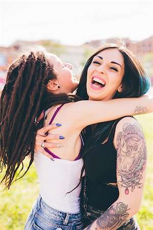 Tattooed young women laughing and hugging in urban park Stock Photo - Premium Royalty-Free, Code: 649-08703317