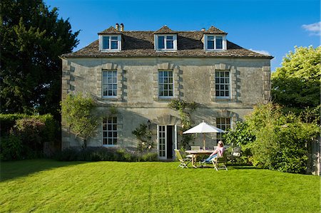 Portrait of mature woman relaxing at garden patio table in front of traditional house, Gloucestershire, England Photographie de stock - Premium Libres de Droits, Code: 649-08703406