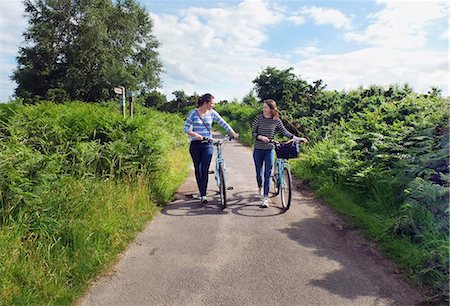 simsearch:649-08232809,k - Two young adults pushing bicycles along country lane Stock Photo - Premium Royalty-Free, Code: 649-08703438