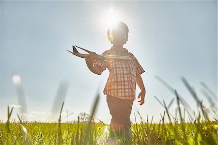 simsearch:649-08894169,k - Boy in sunlit field playing with toy airplane Stock Photo - Premium Royalty-Free, Code: 649-08714084