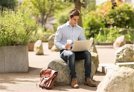 Young businessman reading laptop in city park Stock Photo - Premium Royalty-Free, Code: 649-08714150