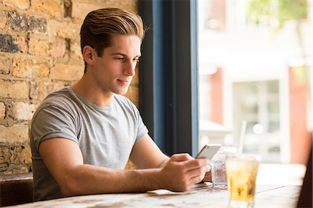 simsearch:649-08824700,k - Young man reading smartphone text in bar Foto de stock - Royalty Free Premium, Número: 649-08714169