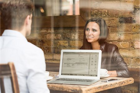 Young businessman and woman working with laptop and talking in cafe Stock Photo - Premium Royalty-Free, Code: 649-08714162