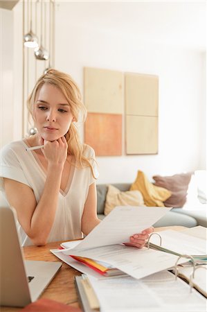 Woman with paperwork looking at laptop Stock Photo - Premium Royalty-Free, Code: 649-08714469