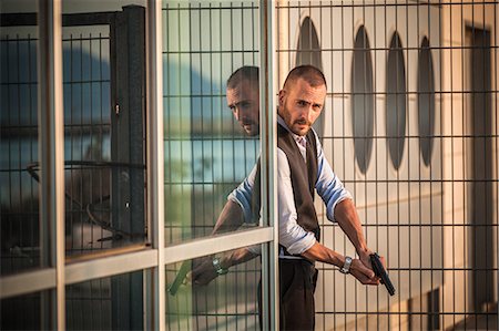 Man in business attire poised behind corner with handgun, Cagliari, Sardinia, Italy Photographie de stock - Premium Libres de Droits, Code: 649-08714603