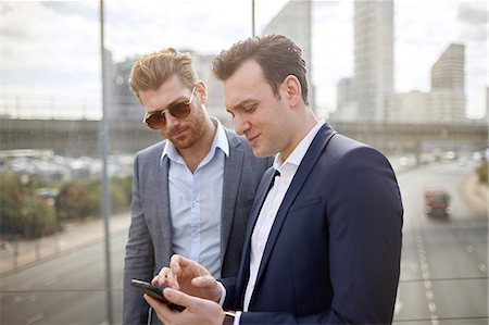 Two businessmen on footbridge texting on smartphone, London, UK Stock Photo - Premium Royalty-Free, Code: 649-08714629