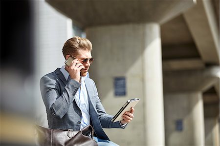 Young businessman talking on smartphone and using digital tablet in city, London, UK Stock Photo - Premium Royalty-Free, Code: 649-08714630