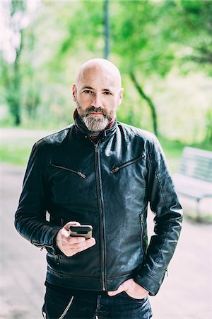 Portrait of mature male motorcyclist holding smartphone Stock Photo - Premium Royalty-Free, Code: 649-08714709