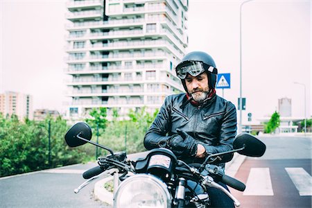 Mature male motorcyclist sitting on motorcycle putting on gloves Stock Photo - Premium Royalty-Free, Code: 649-08714724